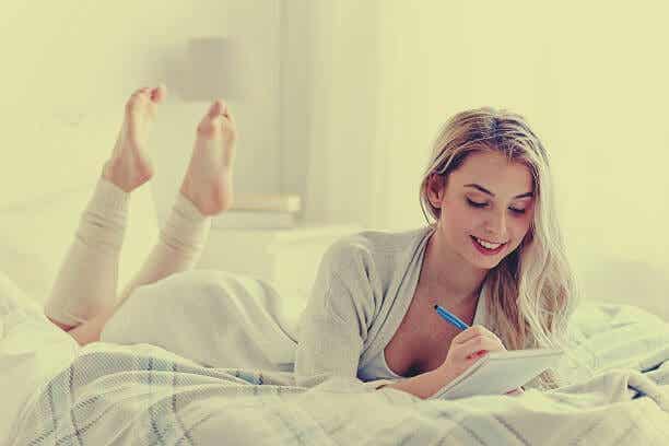Chica en la cama escribiendo el diario de los 5 minutos