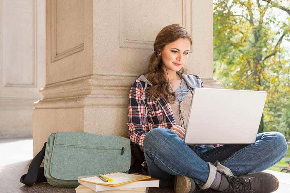 chica apoyada en un pilar y con ordenador que intenta combatir el aburrimiento al estudiar