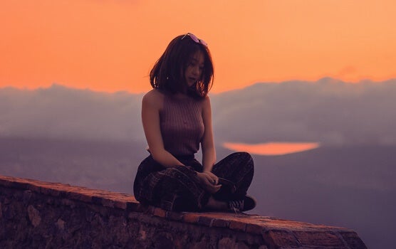 chica sentada sola en un muro simbolizando cómo conectar con una persona introvertida