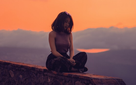 chica sentada sola en un muro simbolizando cómo conectar con una persona introvertida