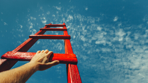 Hombre subiendo por una escalera hacia el cielo para representar la trampa de la motivación