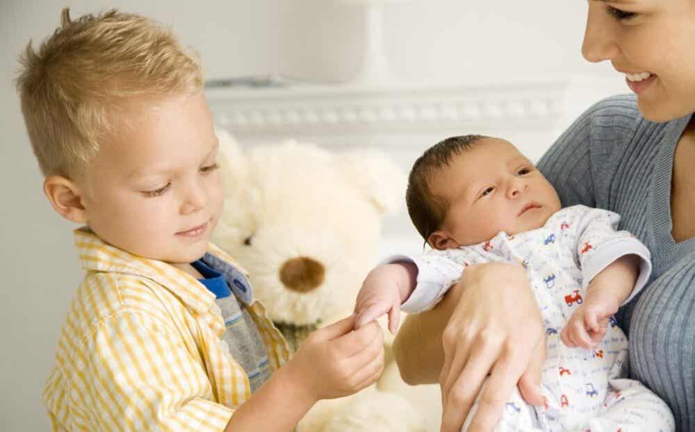 niño tocando a un bebé representando los celos cuando llega un nuevo hermano