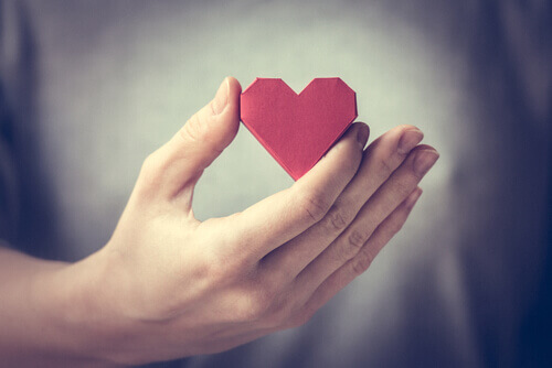 Mano sujetando un corazón rojo