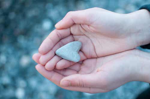 Manos con un corazón de piedra para representar cómo tratar los efectos de la intimidación 
