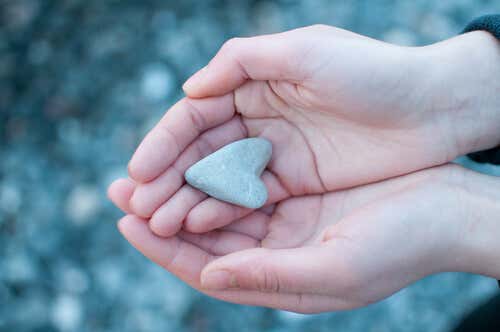 Manos con un corazón de piedra para representar las relaciones afectivas