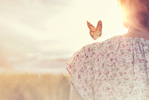 Woman with a butterfly on her shoulder thinking about knowing how to wait