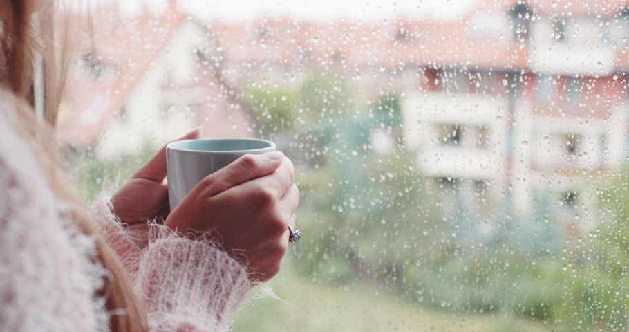 mujer con taza de té escuchando el sonido de la lluvia