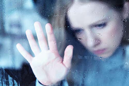 Mujer triste mirando por la ventana debido a un depredador emocional