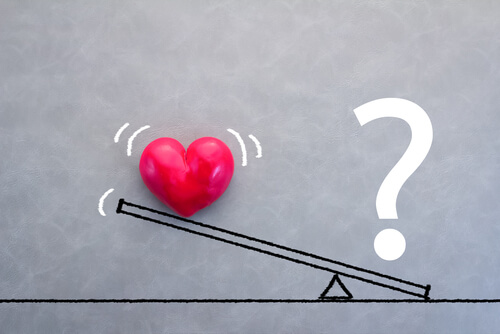 Balanza con un corazón y una interrogación para representar la inseguridad en el amor