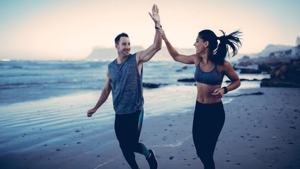 Chico y chica chocando sus manos mientras hacen deporte