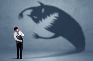 Hombre con miedo a una sombra de monstruo para representar el síndrome de Cronos