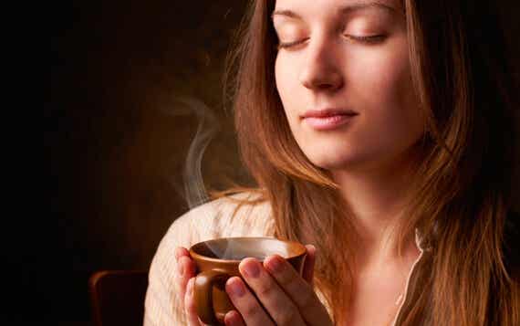 mujer con la taza en la mano disfrutando del olor a café
