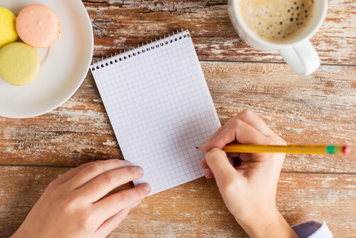 Mujer escribiendo objetivos en una libreta sobre cómo gestionar el tiempo