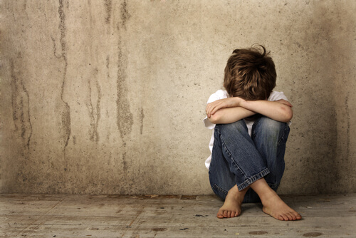 Niño solo y triste sentado en el suelo como efecto del desprecio