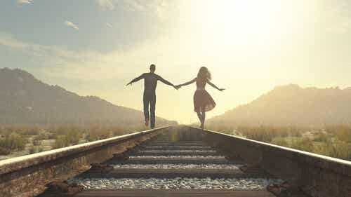 Par løber hånd i hånd på togskinner