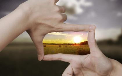 Manos encuadrando una imagen luminosa simbolizando el ejercicio de saborear la vida