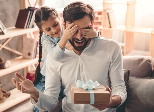 Niña tapando los ojos a su padre para darle un regalo