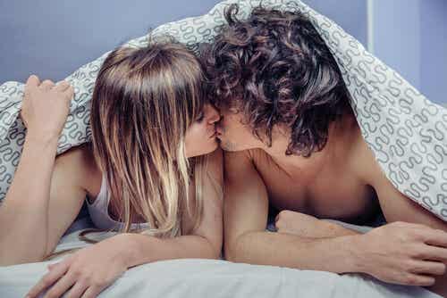 Pareja besándose debajo de las sábanas