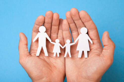 Mano sujetando unas figuras con forma de familia