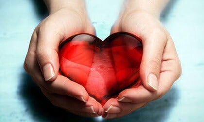 mano con corazón para representar el beneficio de desear que los demás sean felices