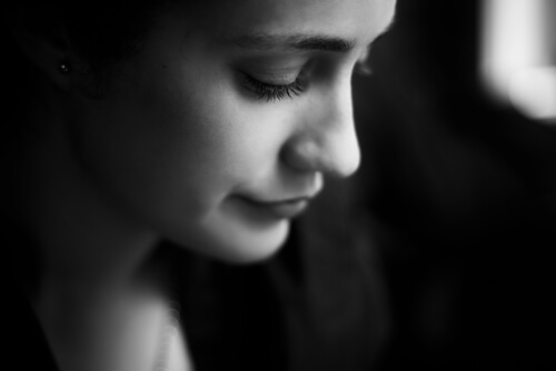 A woman looking down to depict intellectual humility.