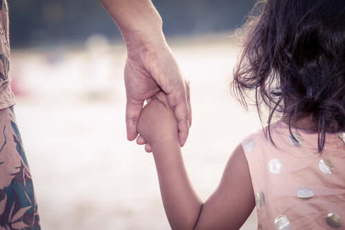 Madre agarrando a su hija de la mano