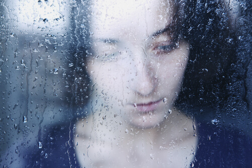 Femme triste derrière une fenêtre