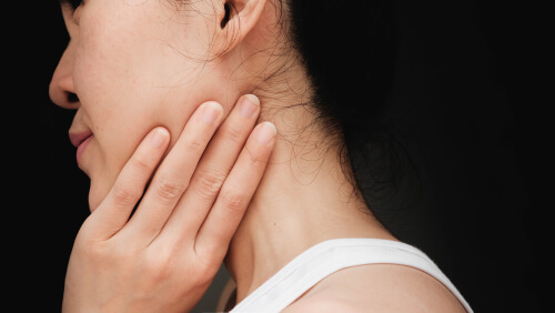 Mujer con una mano en el cuello