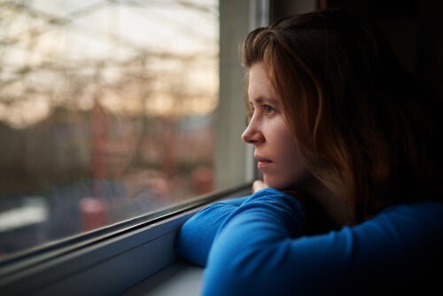 Mujer mirando por la ventana pensando en la importancia de los cuidados emocionales