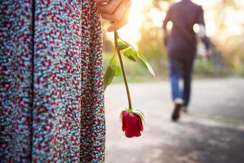 Mujer con una rosa mientras el hombre dice adiós