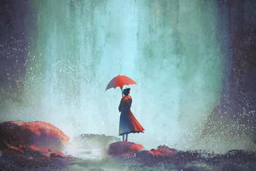 Yksinäinen nainen punaisella sateenvarjolla ja ajattelee, että tunnen itseni yksinäiseksi