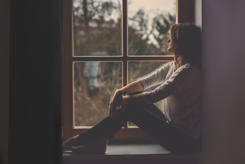 Mujer en una ventana pensando en cuando todo nos da igual