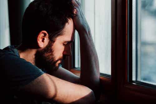 Hombre con ansiedad apoyado en la ventana simbolizando qué decirle a alguien con ansiedad 
