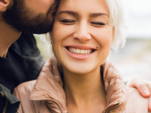 Hombre dando a un beso a su mujer sonriendo
