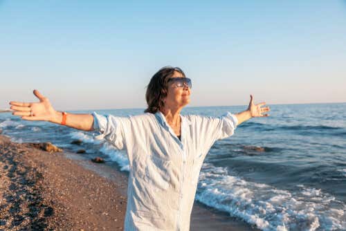 Mujer mayor con los brazos abiertos en la playa