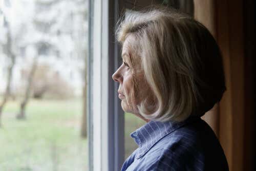 Mujer mayor mirando una ventana