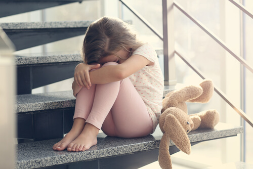 Niña con ansiedad sentada en la escalera