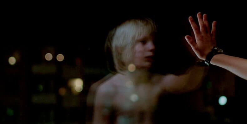 Niño poniendo mano sobre un cristal