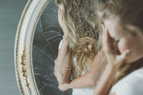 Mujer triste mirándose al espejo