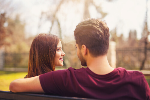 Pareja mirándose en un banco