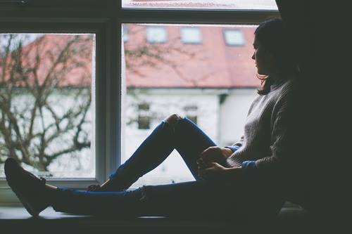 Chica ante mirando el exterior simbolizando lo que vemos desde la ventana