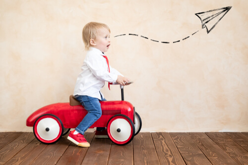 Niño jugando con un coche rojo