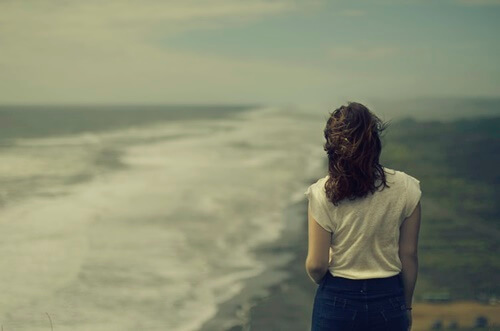 Chica junto a la playa pensando las fortalezas psicológicas