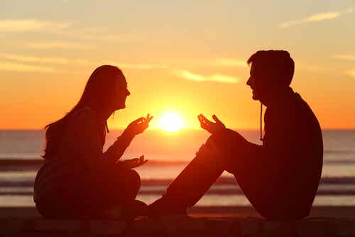 gün batımında karşılıklı oturmuş konuşan çift