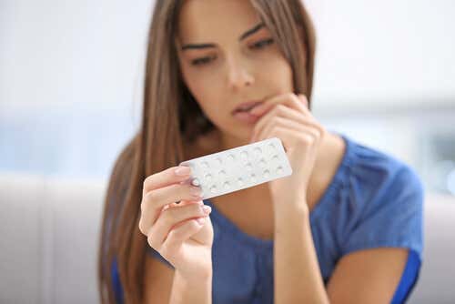 Kvinde med p-piller i hånden overvejer de følelsesmæssige virkninger af p-piller