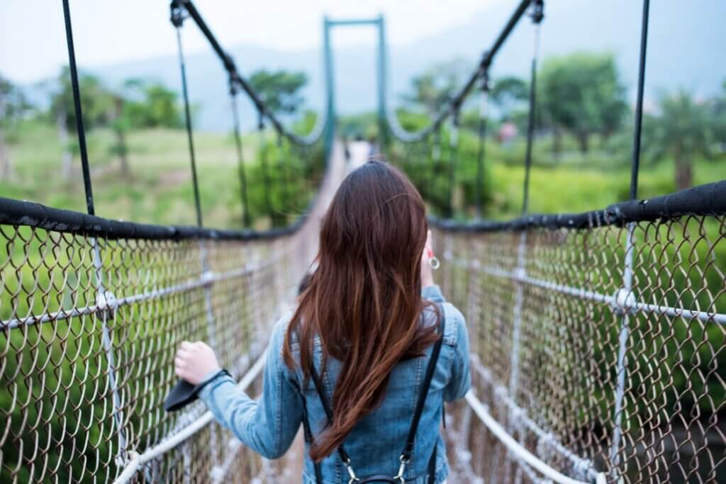 Chica caminando por un puente colgante