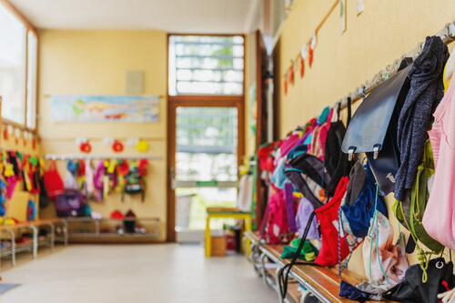 Clase con mochilas colgadas y puerta abierta