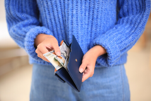 Mujer con dinero en la cartera pensando en las finanzas racionales