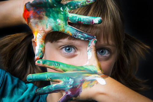 Niña con las manos llenas de pinturas