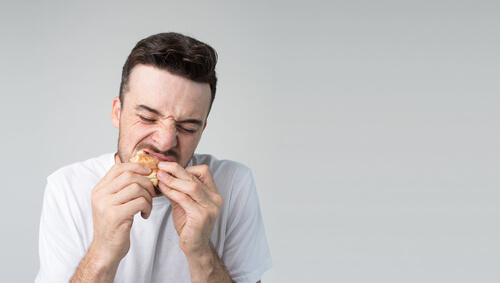 Hombre con hiperfagia comiendo una hamburguesa